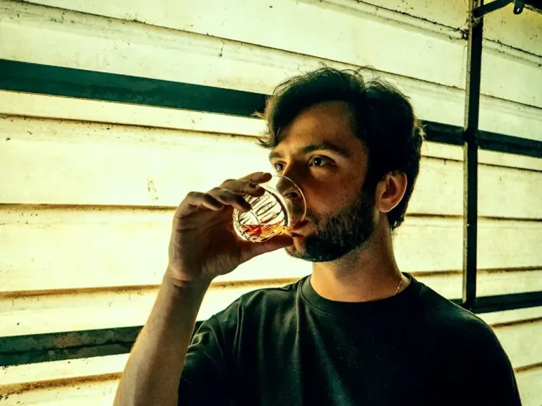 Man sipping from a cut-crystal whiskey glass